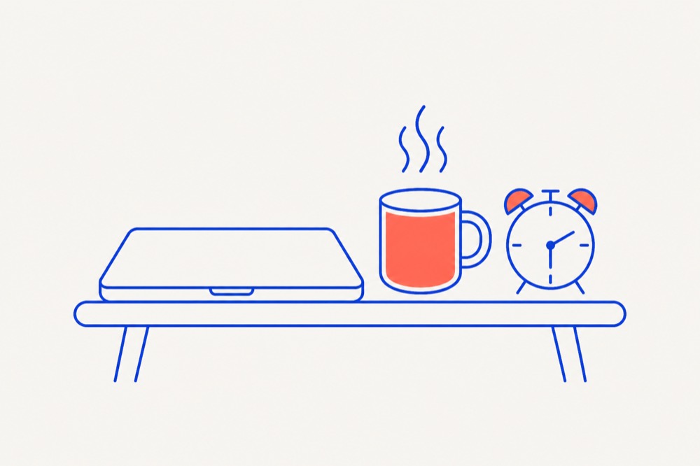 A closed laptop on a table beside a steaming mug and a small alarm clock